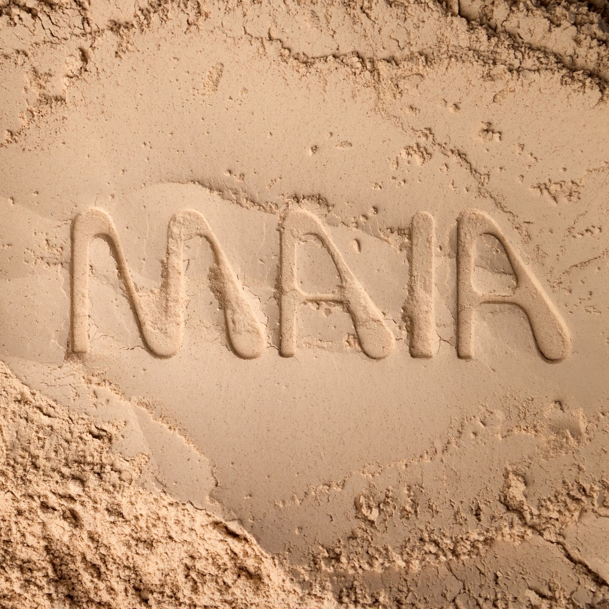 The word "MAIA" is carefully stamped in a smooth, beige powder, showcasing the fine texture of Maia Farms' mushroom-based flour. The image highlights the purity and earth-derived essence of the ingredient.