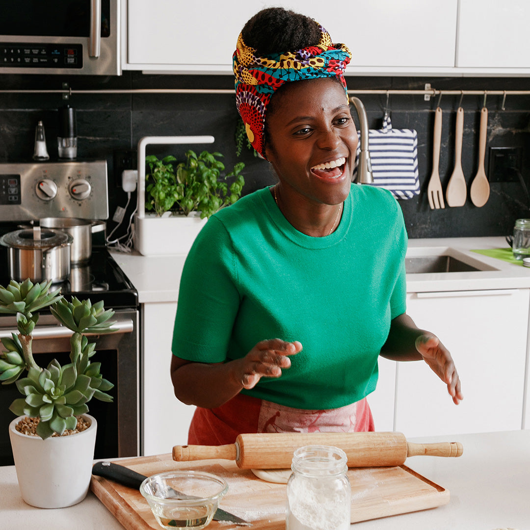 Smiling chef in a vibrant kitchen preparing dough with a rolling pin—capturing the joy of cooking with wholesome, mycelium-powered ingredients from Maia Farms.